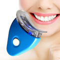 Blue LED teeth whitening device held near a woman's smiling white teeth