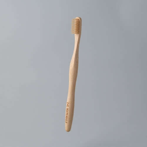 Eco-friendly bamboo toothbrush with soft bristles on a plain grey background