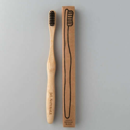 Eco-friendly bamboo toothbrush with black bristles and its matching cardboard packaging